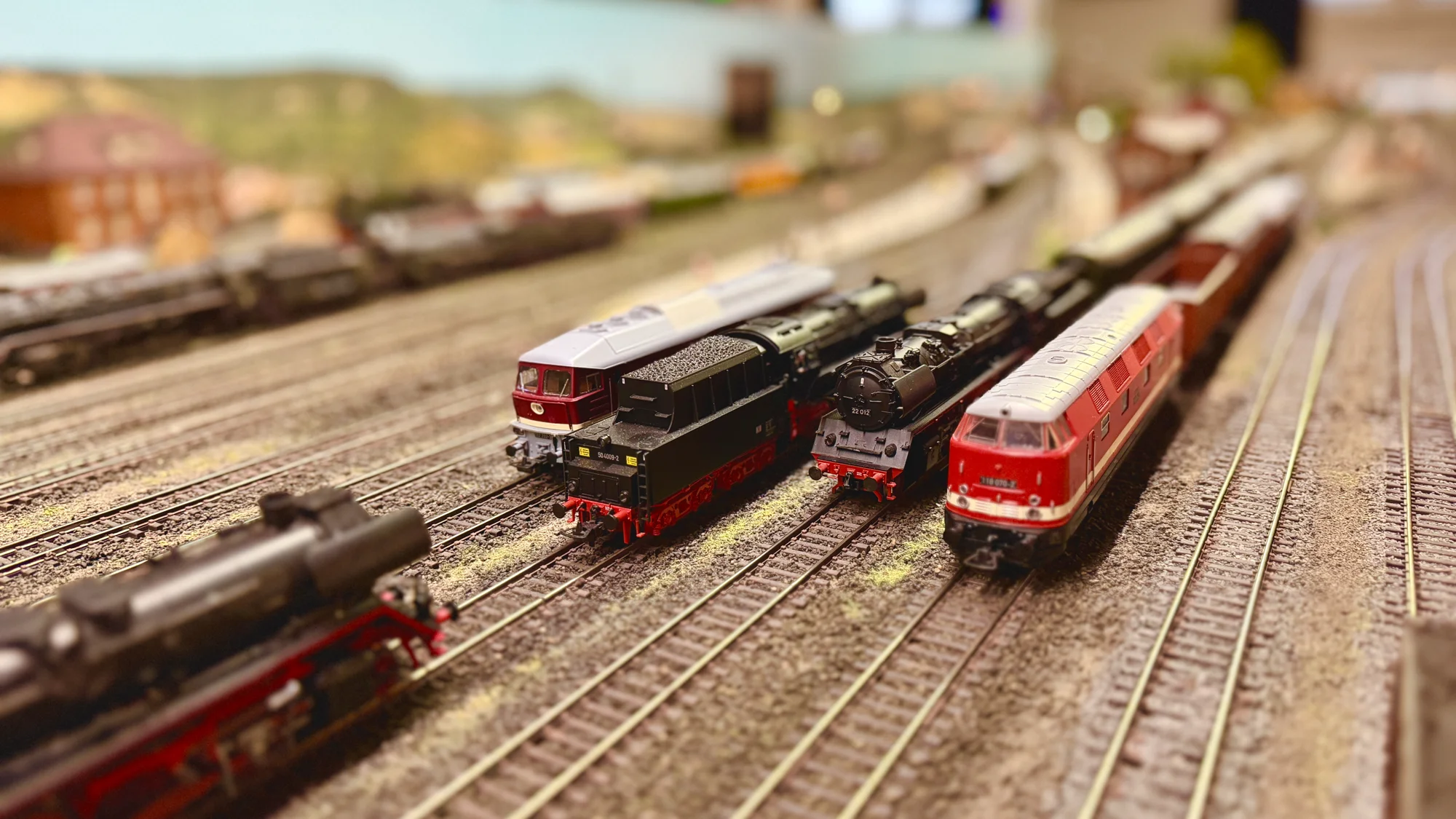 Steam and diesel locomotives lined up in the model railway yard