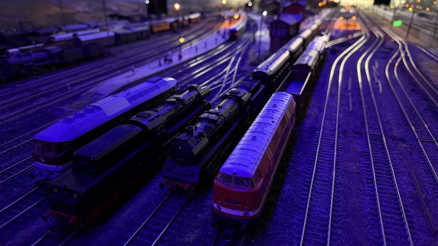 Steam and diesel locomotives in the illuminated yard