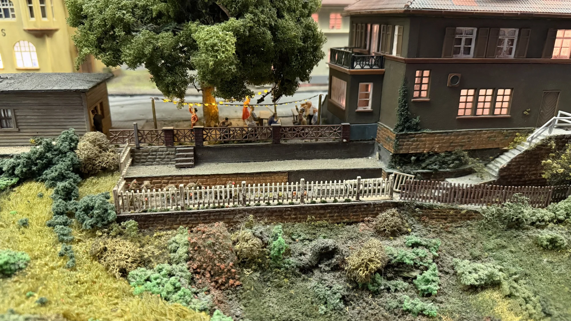 Small gardens beside a brick house and railway