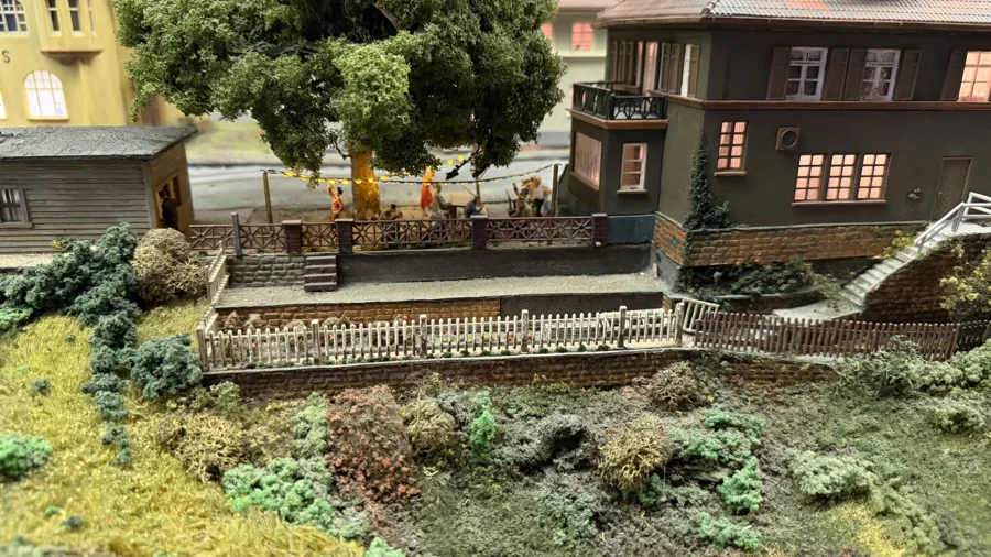 Small gardens beside a brick house and railway